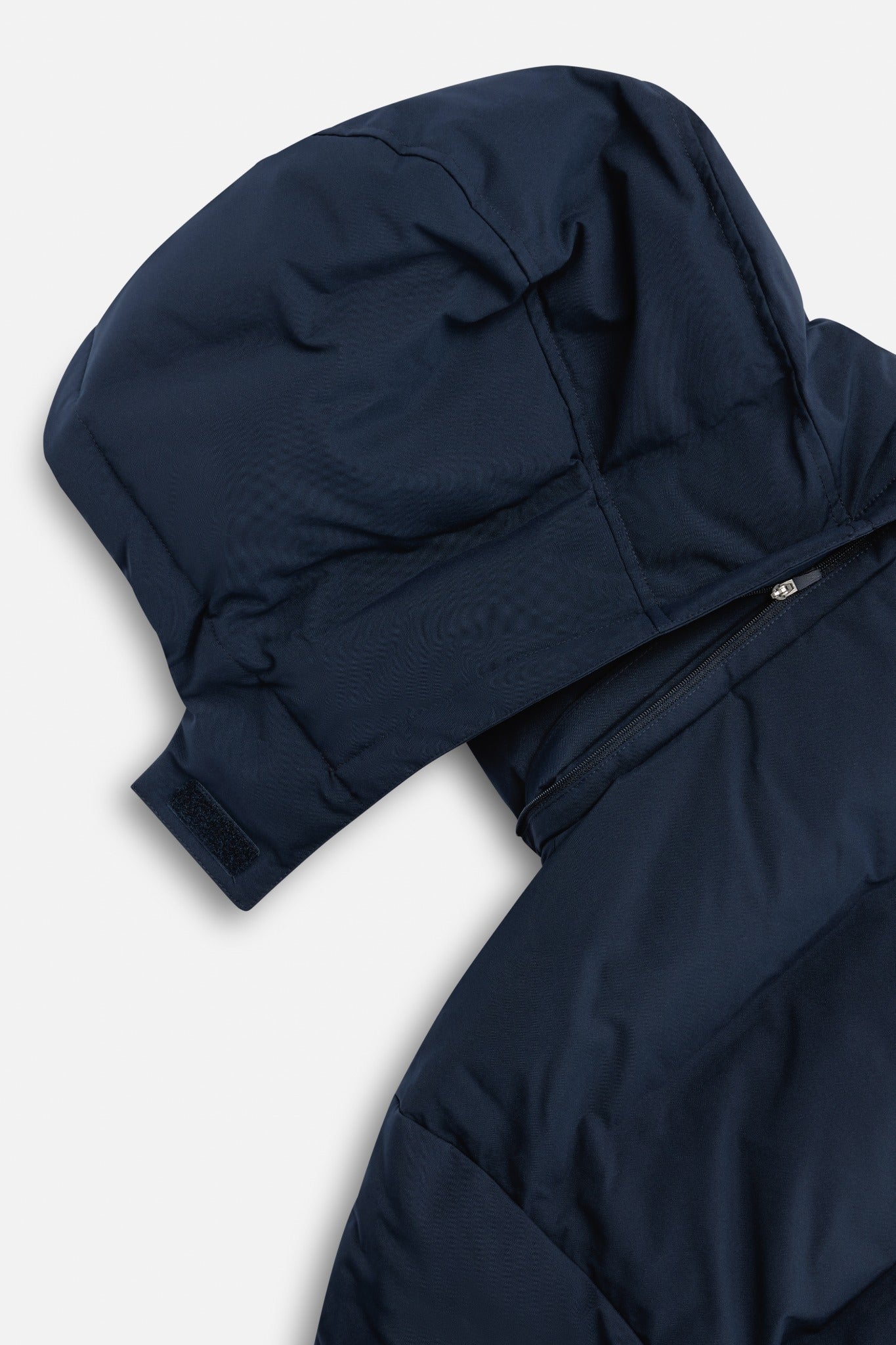 Close-up of the detachable hood and zipper on a navy CASPARA Boreal puffer jacket.